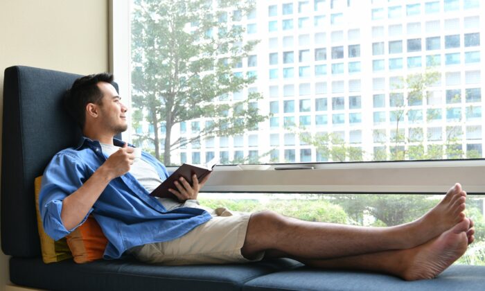 young_man_drinking_coffee_while_sitting_on_sofa_at_home_with_the